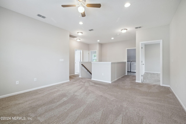 carpeted empty room featuring washer and clothes dryer and ceiling fan