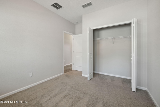 unfurnished bedroom featuring light carpet and a closet