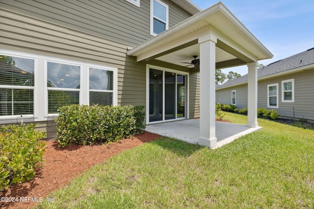 rear view of house with ceiling fan, a patio area, and a lawn