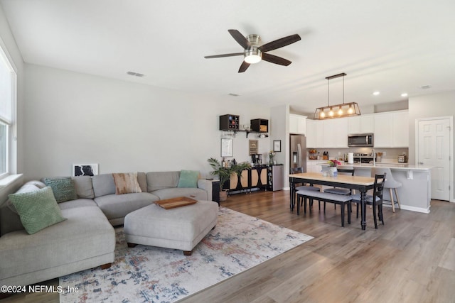 living room with ceiling fan and light hardwood / wood-style flooring