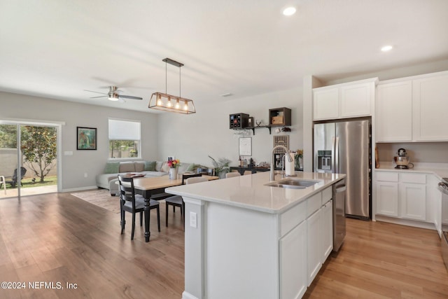 kitchen featuring white cabinetry, sink, pendant lighting, and an island with sink