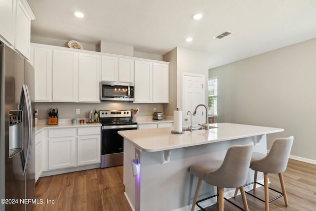 kitchen featuring white cabinetry, wood-type flooring, sink, a kitchen island with sink, and stainless steel appliances