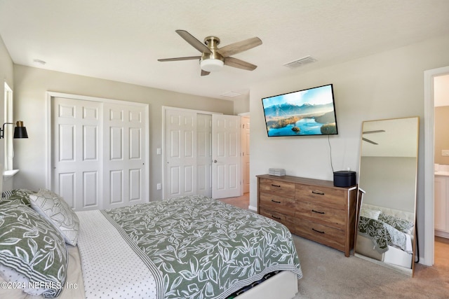 carpeted bedroom featuring ceiling fan and two closets