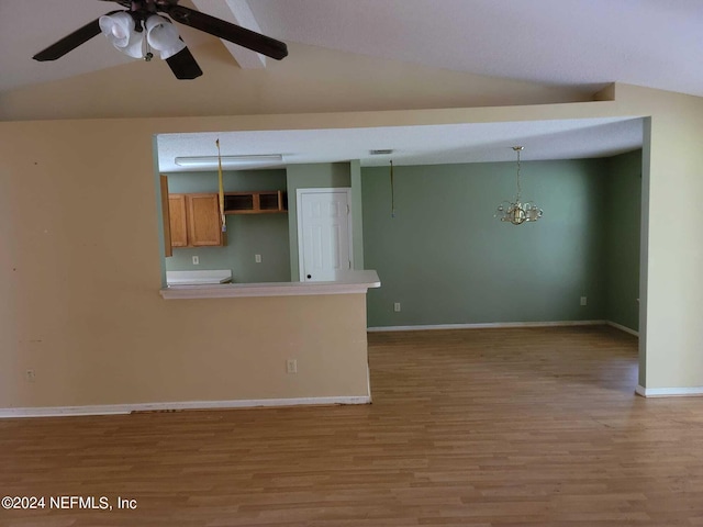 unfurnished living room with vaulted ceiling, ceiling fan with notable chandelier, and light hardwood / wood-style floors