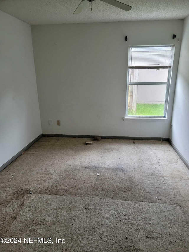 carpeted empty room with ceiling fan and a textured ceiling