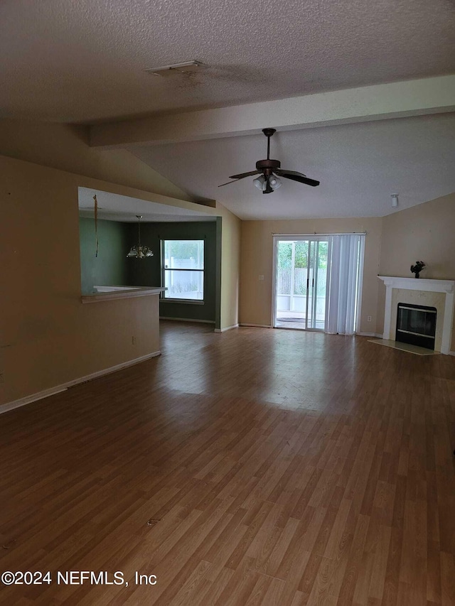 unfurnished living room featuring a textured ceiling, lofted ceiling with beams, hardwood / wood-style floors, and ceiling fan