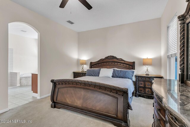 carpeted bedroom featuring ensuite bath and ceiling fan