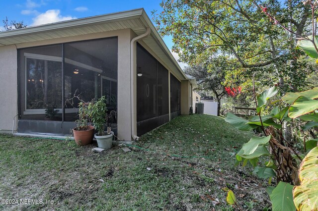 view of side of home featuring a sunroom and a lawn