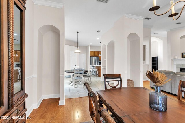 dining area featuring a fireplace, light hardwood / wood-style flooring, and ornamental molding