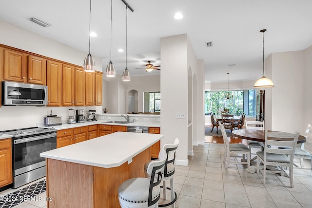 kitchen with appliances with stainless steel finishes, sink, hanging light fixtures, light tile patterned flooring, and ceiling fan