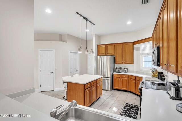 kitchen featuring light tile patterned flooring, stainless steel appliances, hanging light fixtures, and a kitchen island