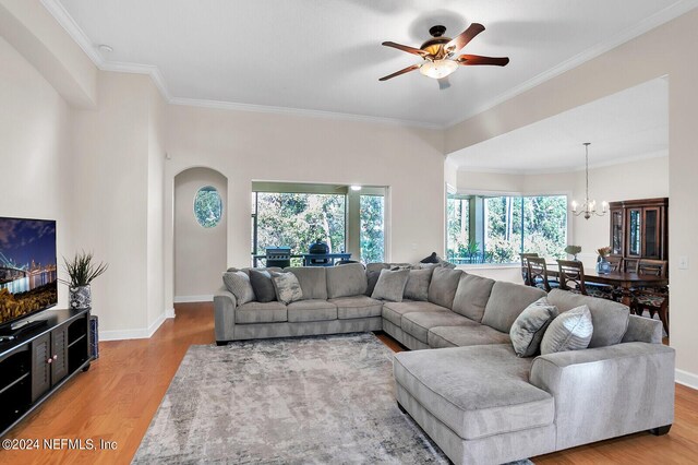 living room featuring ornamental molding, light hardwood / wood-style flooring, a wealth of natural light, and ceiling fan with notable chandelier