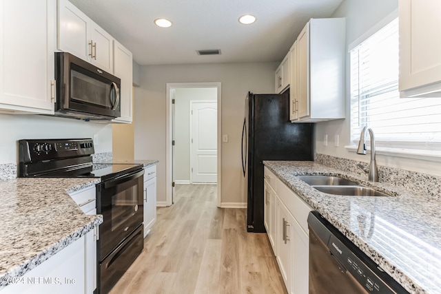 kitchen with white cabinets, light wood-type flooring, light stone counters, sink, and black appliances