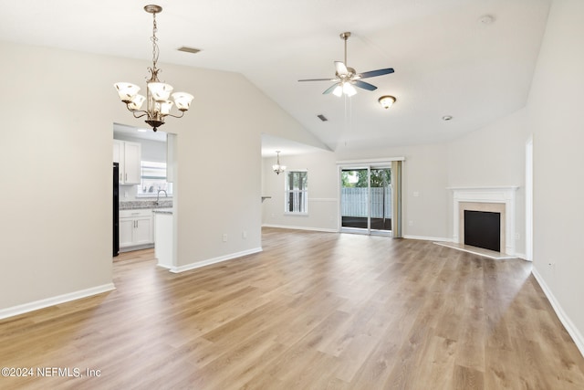 unfurnished living room featuring ceiling fan with notable chandelier, a high end fireplace, light hardwood / wood-style flooring, sink, and vaulted ceiling