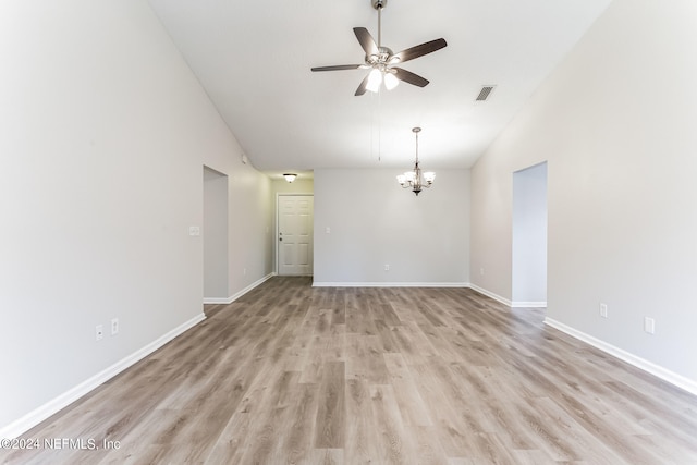 empty room with light hardwood / wood-style flooring, ceiling fan with notable chandelier, and high vaulted ceiling