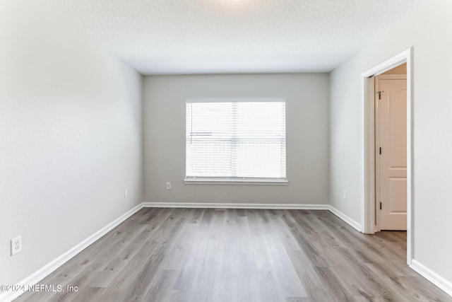 empty room with a textured ceiling and light wood-type flooring