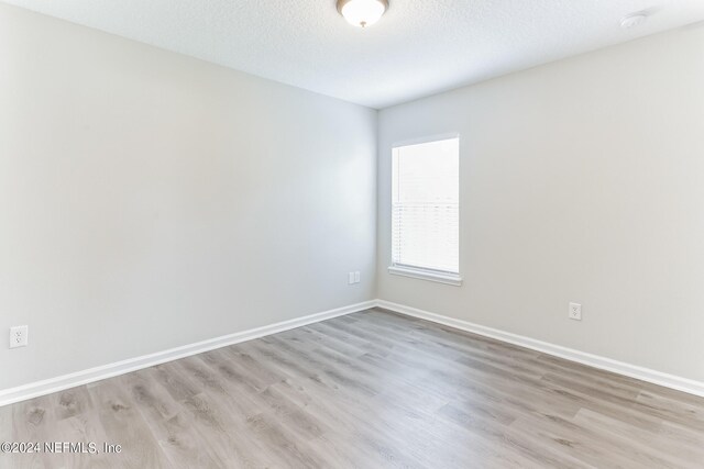 empty room with a textured ceiling and light wood-type flooring