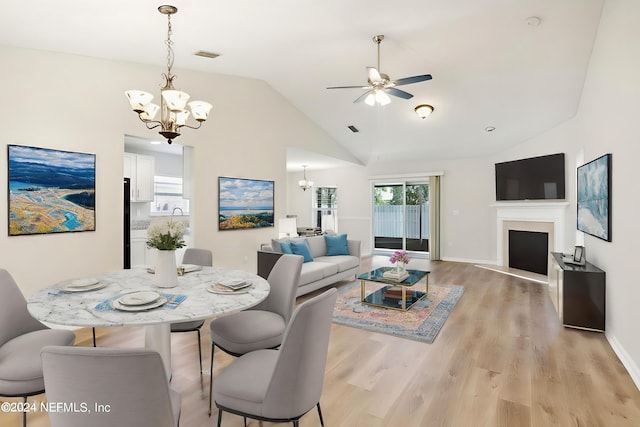 dining area featuring ceiling fan with notable chandelier, lofted ceiling, and light hardwood / wood-style flooring