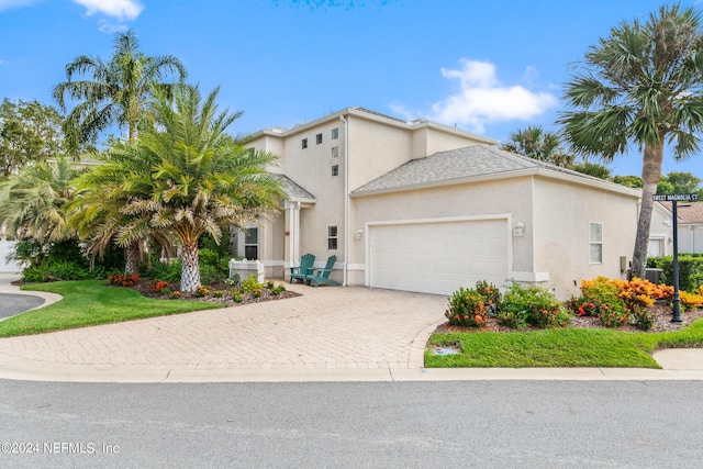 view of front of house featuring a garage, roof with shingles, decorative driveway, a front lawn, and stucco siding