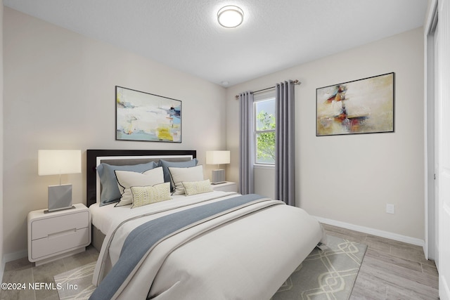 bedroom with a textured ceiling and light hardwood / wood-style flooring