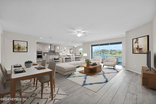 living room featuring a textured ceiling, light hardwood / wood-style floors, and ceiling fan