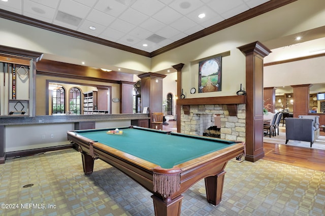 recreation room with a stone fireplace, decorative columns, crown molding, light wood-type flooring, and pool table