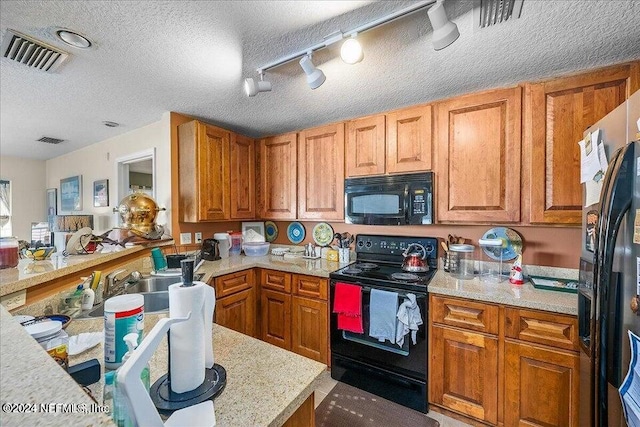 kitchen with rail lighting, kitchen peninsula, a textured ceiling, black appliances, and sink