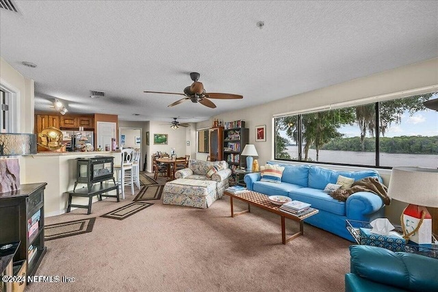 carpeted living room featuring a textured ceiling, ceiling fan, and plenty of natural light