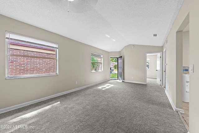 spare room with carpet, vaulted ceiling, and a textured ceiling