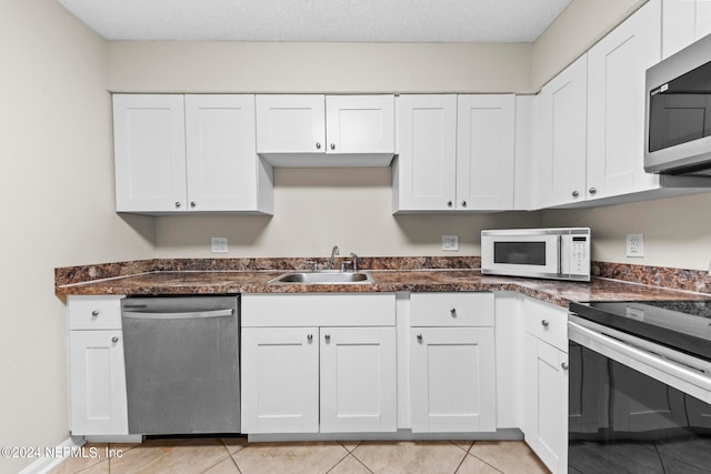 kitchen featuring sink, white cabinetry, light tile patterned floors, and stainless steel appliances