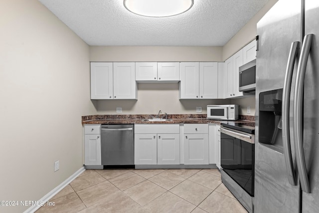 kitchen with sink, appliances with stainless steel finishes, white cabinets, and light tile patterned floors