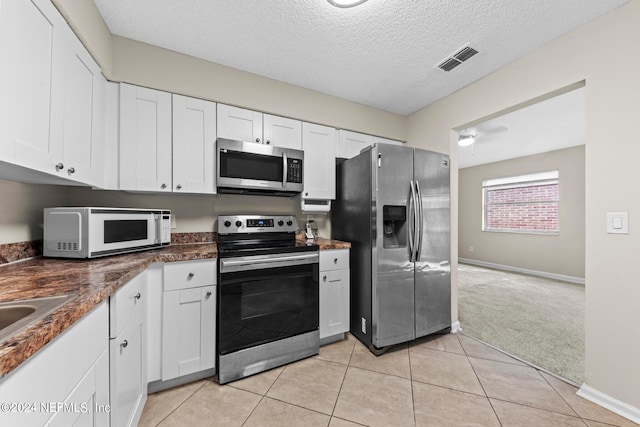 kitchen with white cabinetry, light carpet, appliances with stainless steel finishes, and a textured ceiling