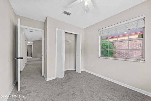 unfurnished bedroom with carpet flooring, a textured ceiling, a closet, and ceiling fan