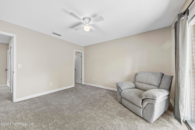 sitting room with light carpet, a textured ceiling, and ceiling fan