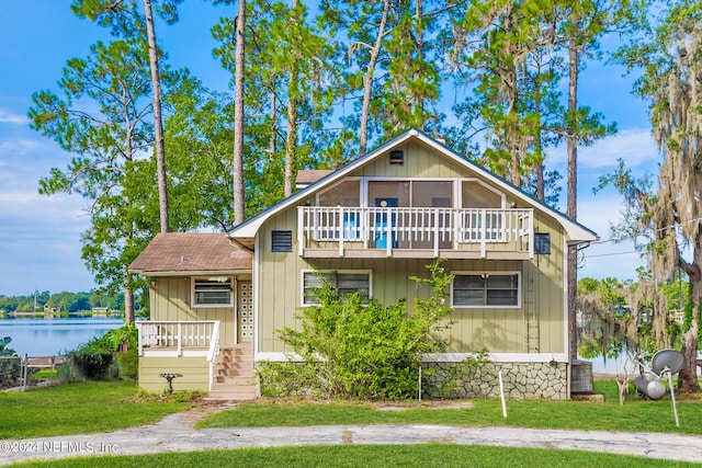 view of front of home featuring a balcony, a water view, and a front lawn