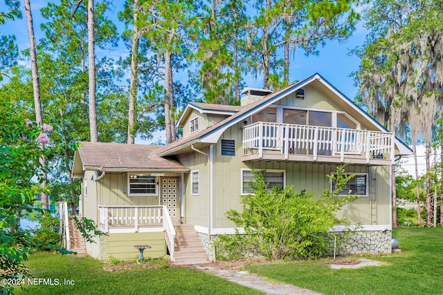 view of front of home with a balcony and a front yard