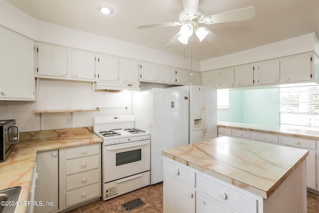 kitchen with ceiling fan, dark tile patterned floors, white cabinets, white appliances, and a center island