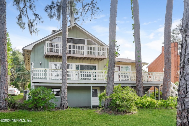 rear view of house with a balcony and a yard