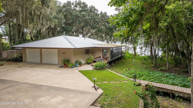 view of front of property featuring concrete driveway, stucco siding, metal roof, an attached garage, and a front yard