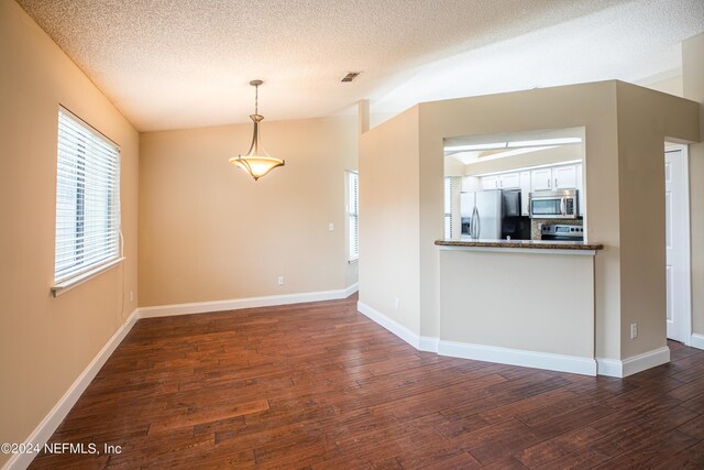 kitchen with white cabinetry, stainless steel appliances, vaulted ceiling, and dark wood-type flooring