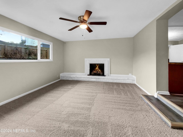 unfurnished living room with a fireplace, ceiling fan, and carpet flooring