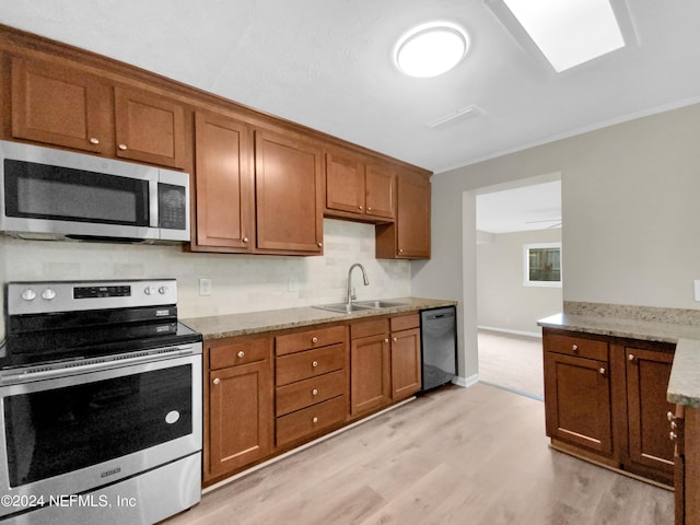 kitchen featuring light wood-type flooring, sink, stainless steel appliances, and light stone counters