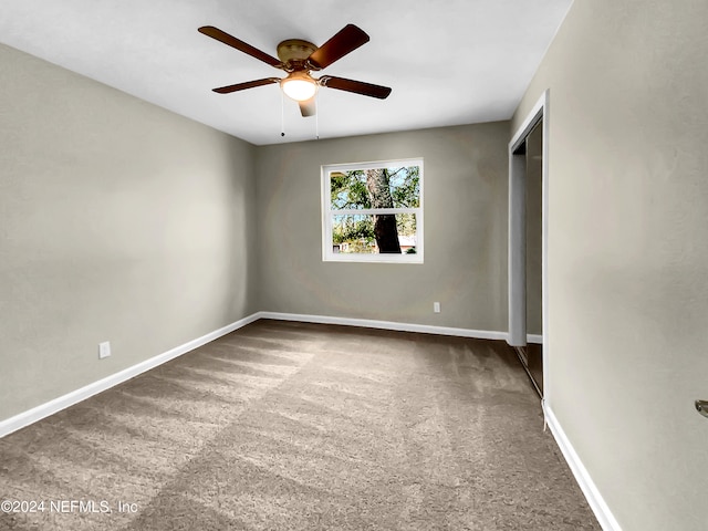 carpeted spare room with ceiling fan