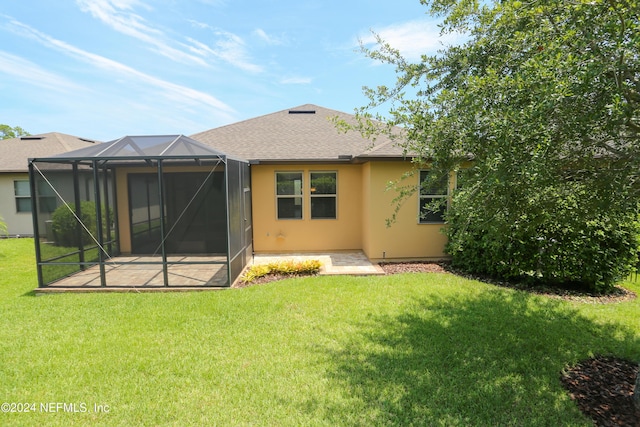 rear view of house with a yard, glass enclosure, and a patio