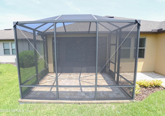 rear view of house featuring a patio and glass enclosure