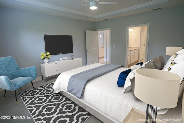 bedroom with a tray ceiling, ensuite bath, and ceiling fan