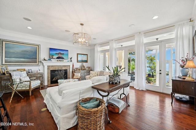 living room with french doors, dark wood finished floors, ornamental molding, a glass covered fireplace, and a chandelier