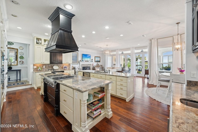 kitchen with light stone counters, a kitchen island, hanging light fixtures, open shelves, and glass insert cabinets