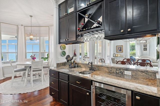 kitchen featuring decorative light fixtures, beverage cooler, a sink, dark wood-style floors, and glass insert cabinets