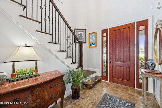 entrance foyer featuring a towering ceiling, stairs, and baseboards